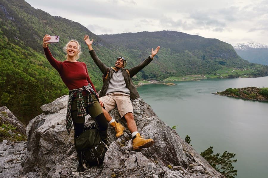 To fjellvandrere på en topp med utsikt over en fjord